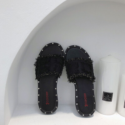 

Chic slippers of the same style for women wearing fashionable flat-bottomed slippers on windy sand beach of Baitains Port in summe
